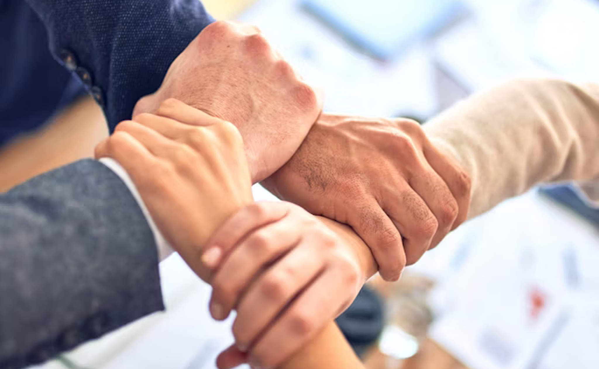Team members joining hands to represent collaboration and commitment